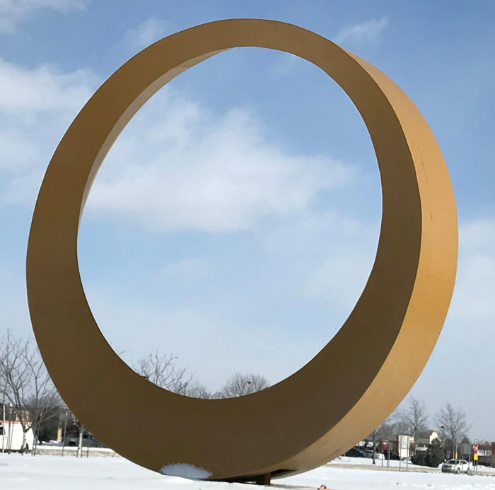 Large yellow circular monument outdoors under blue sky