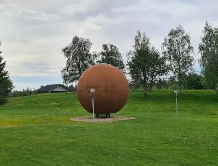 Rust-colored spherical monument on green grassy field