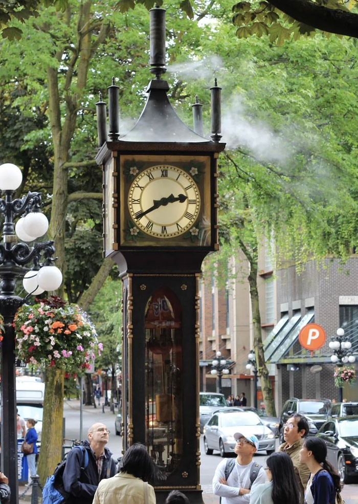 Historic steam clock monument with people observing