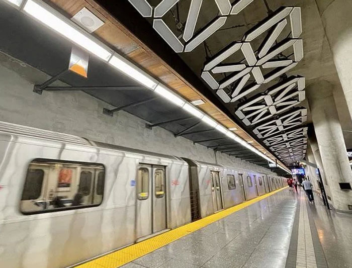 Modern subway platform with silver train and geometric ceiling design