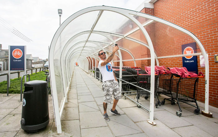 Man taking selfie inside awkward trolley park shelter ugly monument