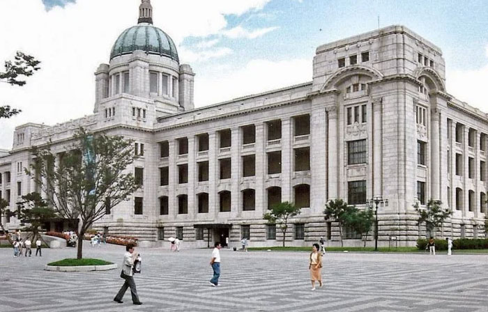 Ugly large classical building with dome and people walking nearby