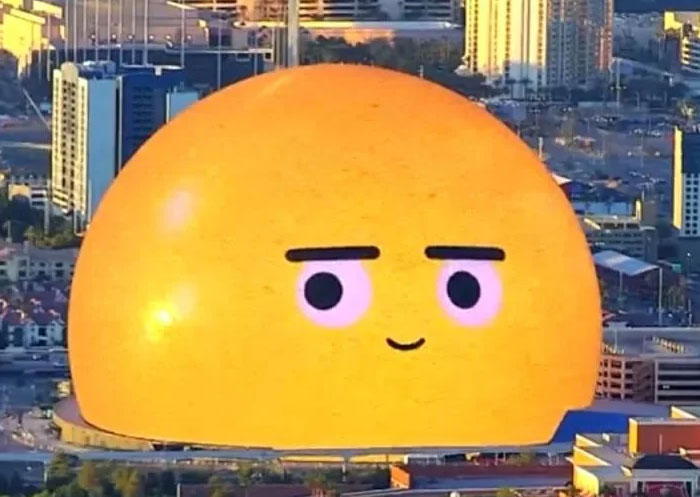 Large yellow dome building with a face resembling an emoji in city