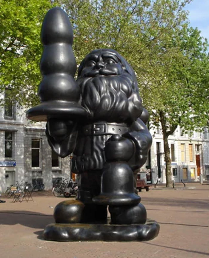 Black gnome statue holding an unusual shaped object in urban area