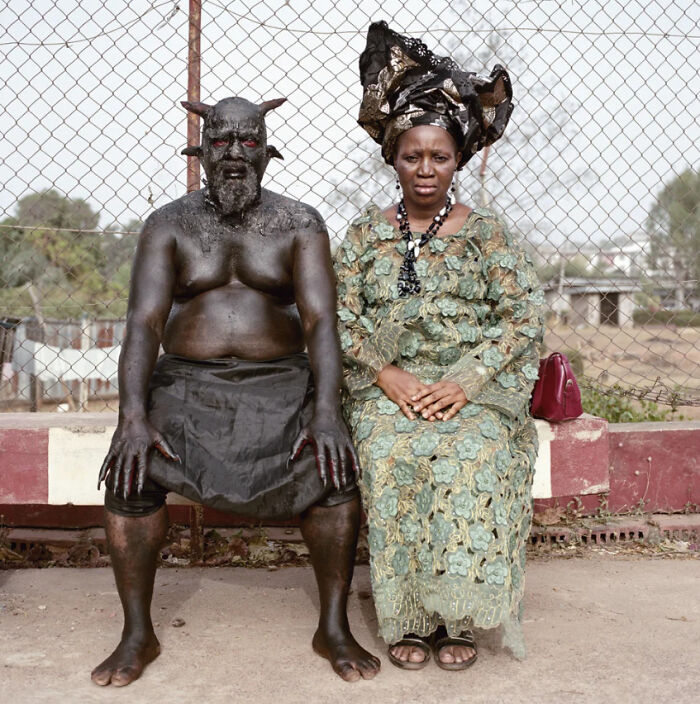 Man with black paint and horns sitting next to woman in traditional dress creepy photo