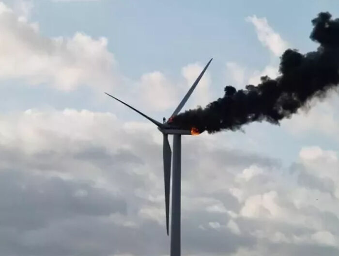 Creepy wind turbine on fire emitting thick black smoke