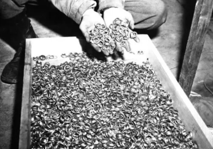 Black and white creepy photo of hands holding numerous small metal rings over a tray