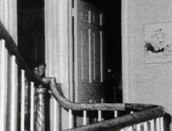 Creepy photo showing ghostly figure on staircase in dimly lit hallway