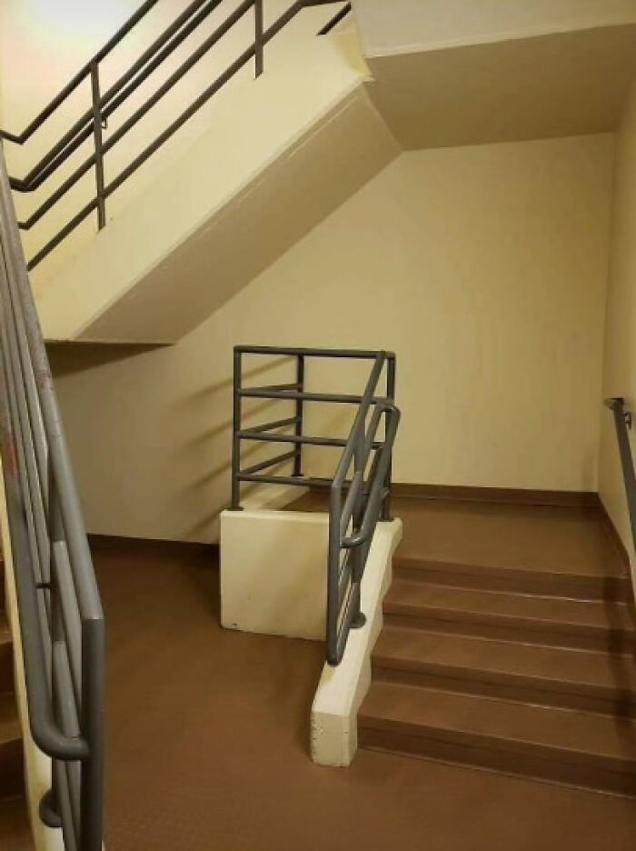 Absurd architecture and design fails: a set of indoor stairs with a short, isolated railing in the middle of a landing.