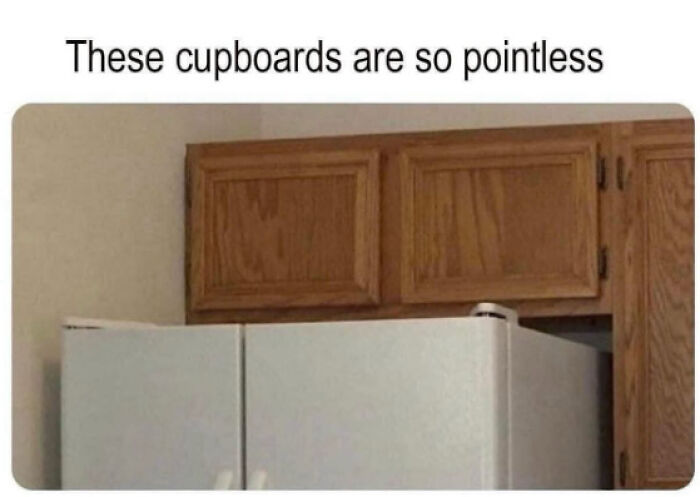 A poorly designed kitchen with cupboards above a refrigerator that are too high to be useful, an architecture and design fail.
