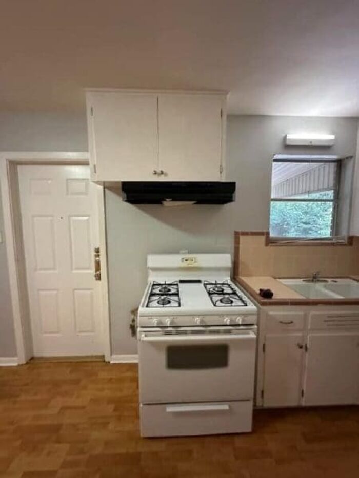 An awkward kitchen layout with a range and oven positioned directly below a small wall cabinet, an architecture and design fail.