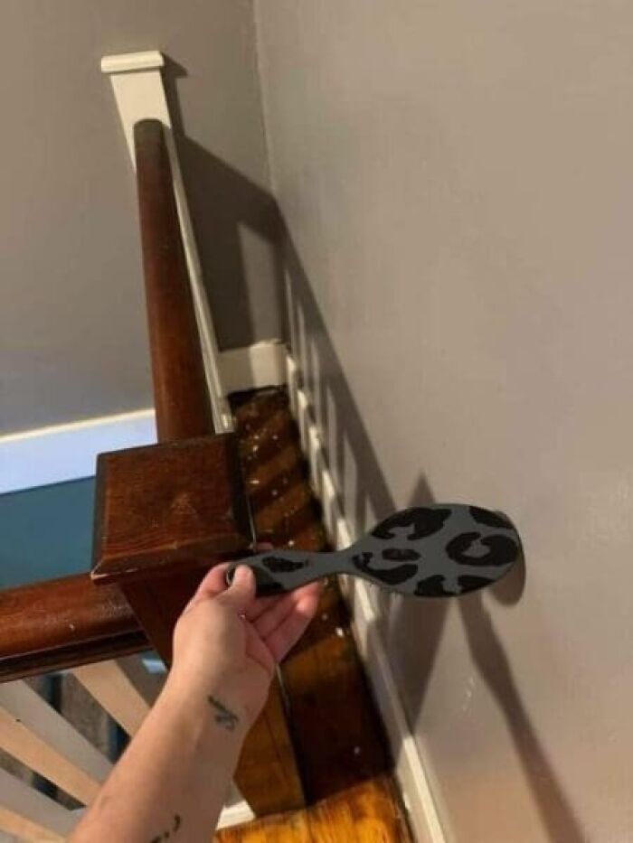 A hand holding a hairbrush that cant reach the wall due to a banister post blocking it, an architecture and design fail.