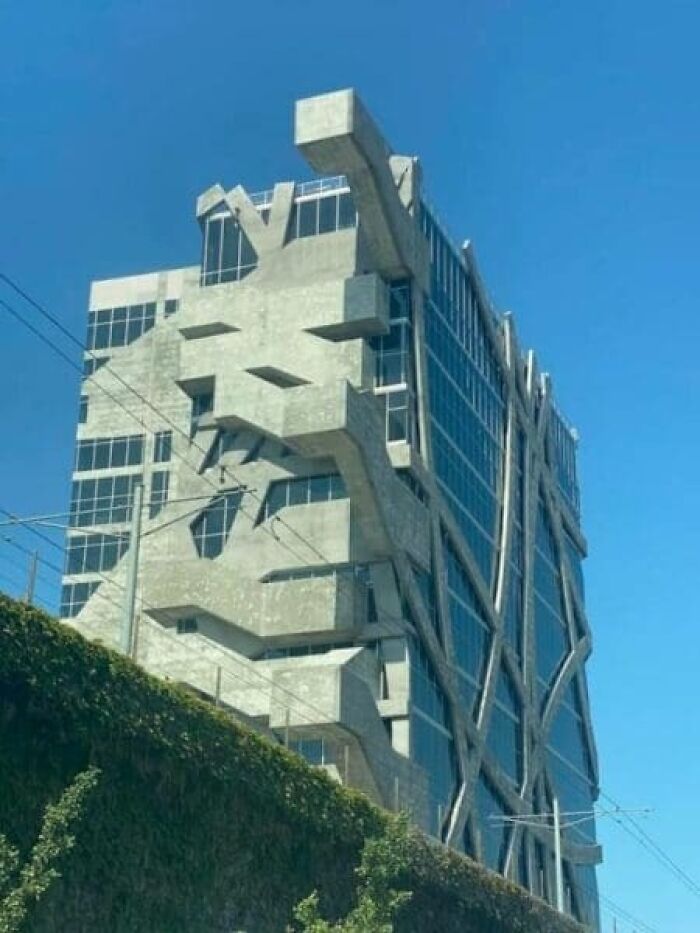 A modern concrete and glass building with unusual, protruding concrete beams, showcasing architecture and design fails.