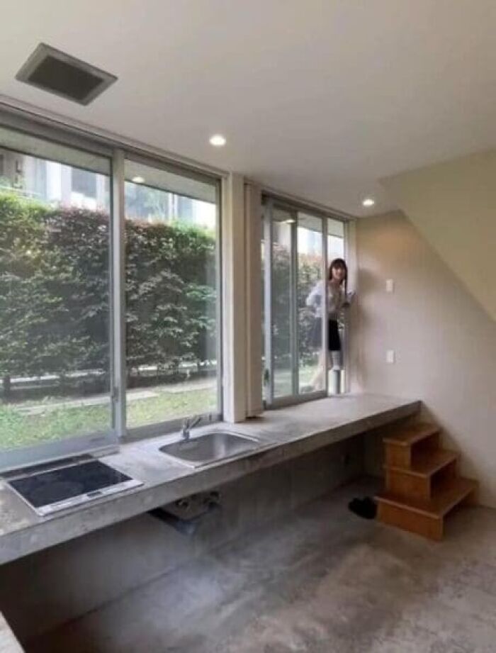 A kitchen counter with a sink and stovetop that is too high, next to a window, an architecture and design fail.