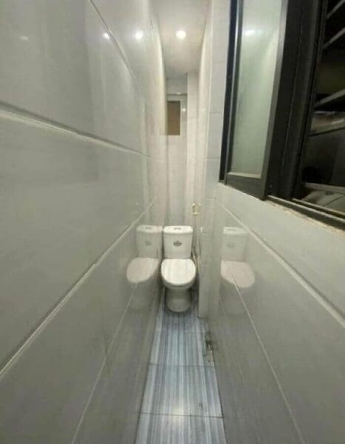 Two toilets crammed side-by-side in a very narrow, tiled bathroom, showcasing an architecture and design fail.
