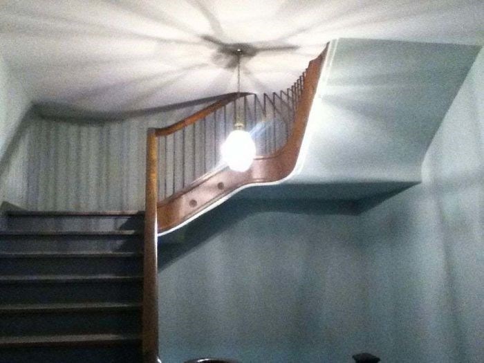 An oddly designed staircase with a curving banister and light fixture demonstrating a design fail.