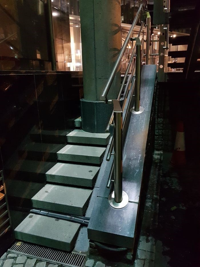 An external staircase with a railing that extends far beyond the steps, creating an awkward architecture and design fail.