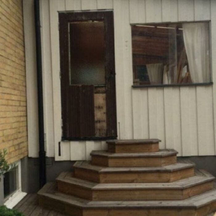 A wooden door with steps leading up to it, but the door is cut in half, an architecture and design fail.