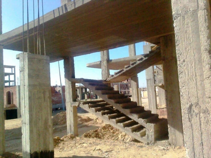 An architecture fail featuring an incomplete concrete building with a staircase leading directly to a wall.
