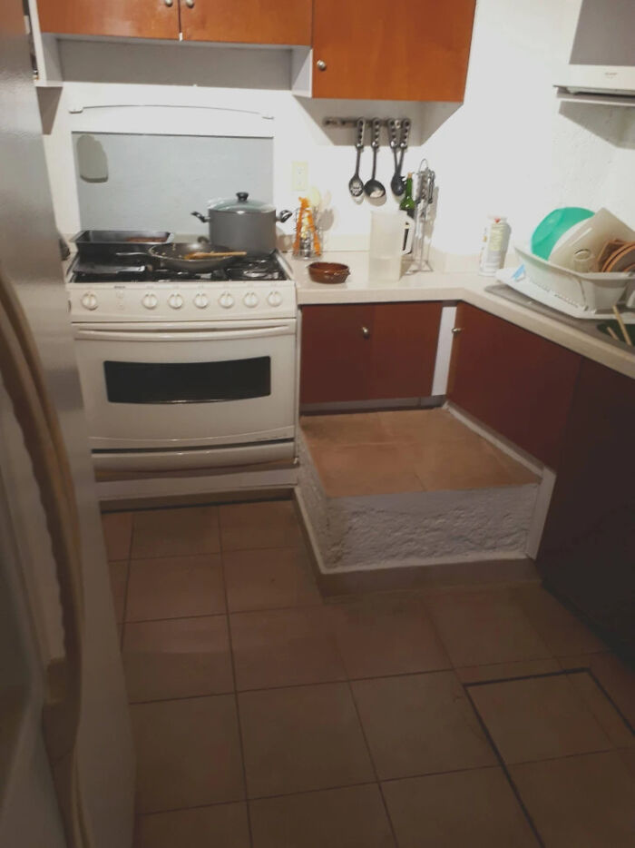 A design fail in a kitchen with a raised concrete platform in front of a lower cabinet section.