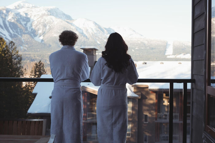 Couple in bathrobes looking at mountains during getaway