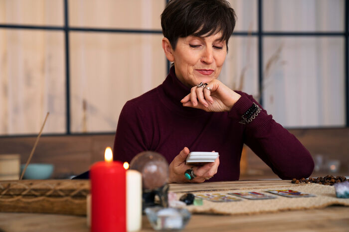 Woman reading tarot cards at table, representing relationships that derailed and breakup stories