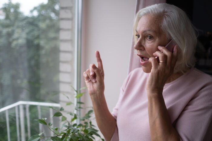 Elderly woman angrily talking on phone depicting intense breakup arguments