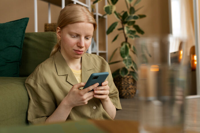 Worried woman reading phone messages at home
