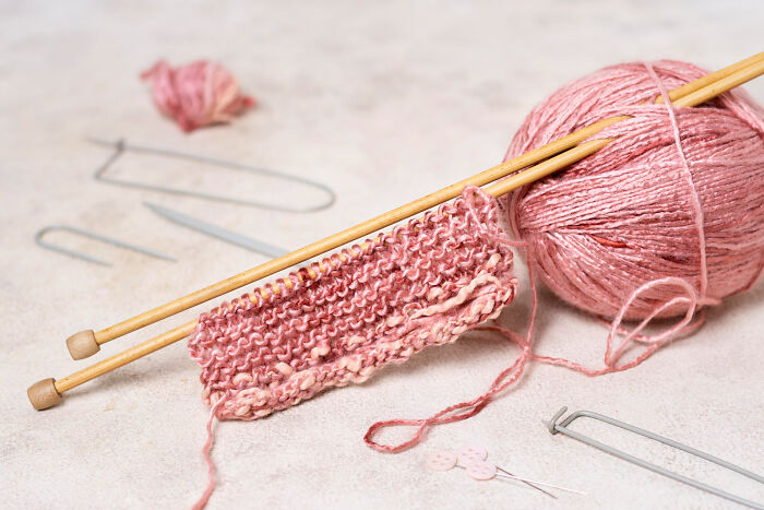 Pink knitting project with needles representing relationship hobbies