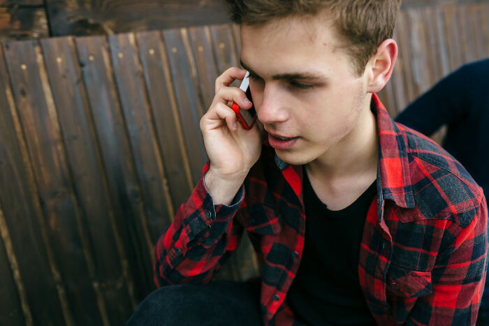Young man in plaid shirt talking on phone looking concerned