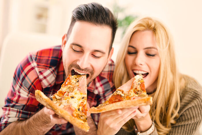 Couple eating pizza together in a casual setting enjoying food and laughter