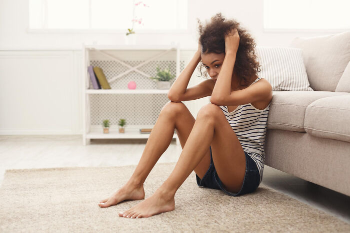 Woman sitting on floor upset during relationship struggle