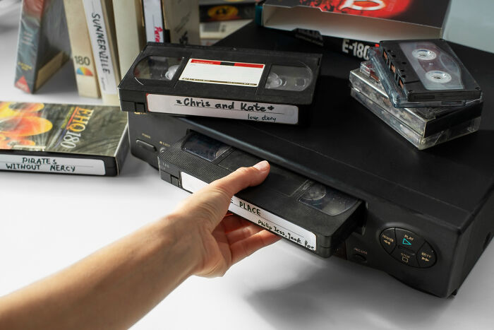 Hand inserting VHS tape labeled love story into player