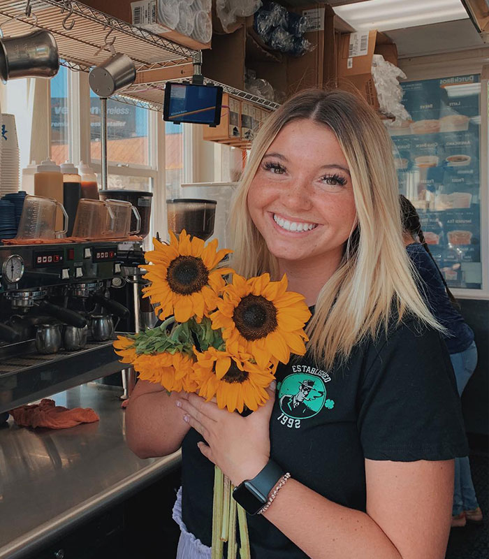 Smiling young woman holding sunflowers inside a cafe