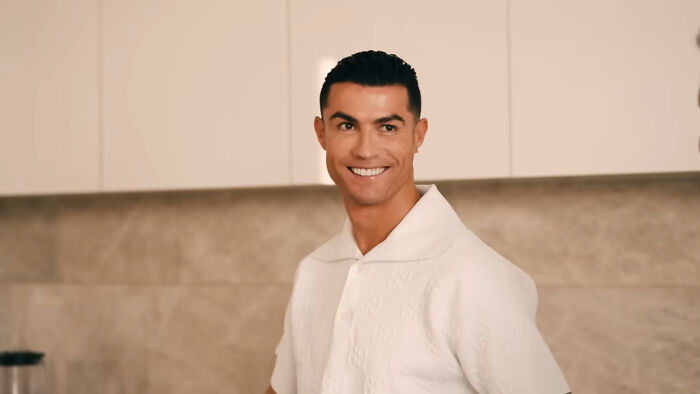 Cristiano Ronaldo, a celebrity whose fame ran out, smiling in a white shirt in a kitchen.
