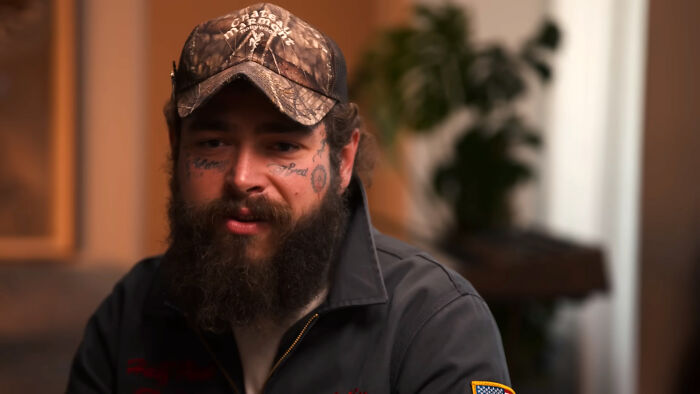 Post Malone, a celebrity whose fame ran out, wearing a camouflage hat and a dark shirt.
