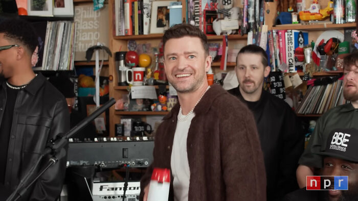 Justin Timberlake, a celebrity whose fame might have run out, smiles in a room with musical instruments and records.