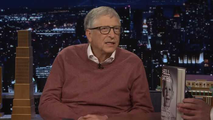 Bill Gates discusses AI's impact on jobs and safe careers, with his book visible.