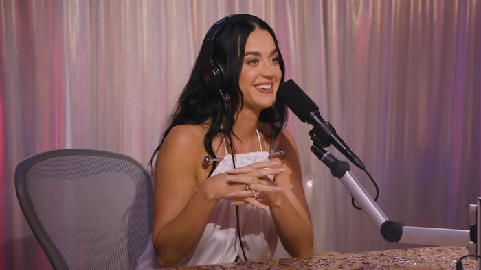 Katy Perry, a celebrity whose fame might have run out, wears headphones and speaks into a microphone.