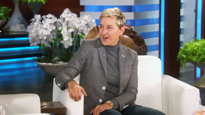 Person sitting on talk show set in casual outfit discussing relationships
