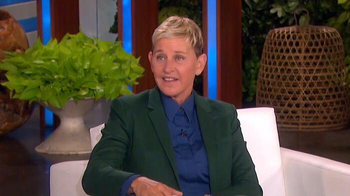Ellen DeGeneres, a celebrity whose fame ran out, in a green suit on a white sofa.