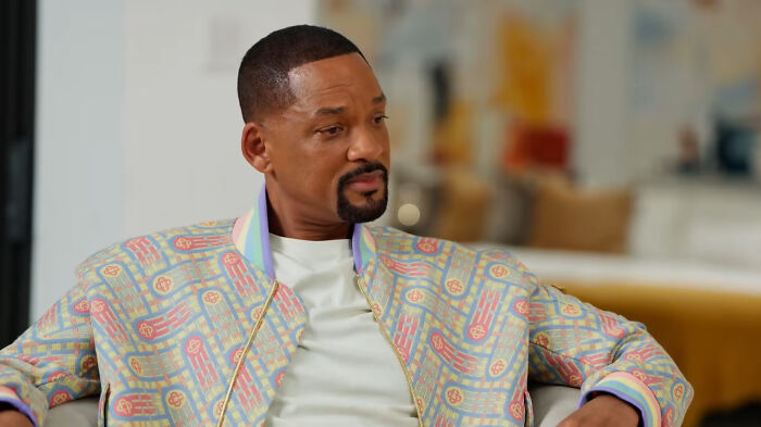 Will Smith, a celebrity whose fame ran out, looking reflective in a colorful jacket.