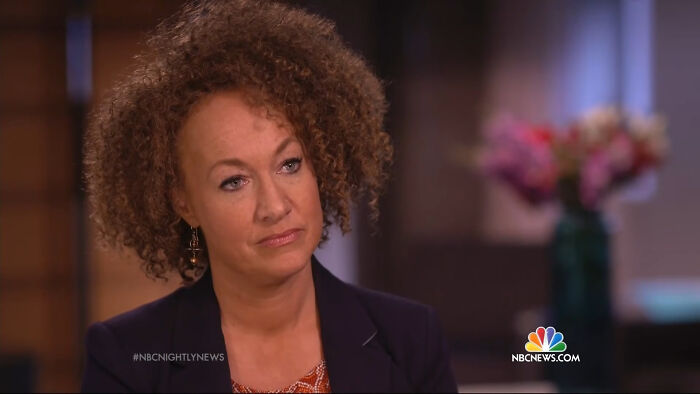 A woman with curly hair looking intently, featured in a segment on celebrity scandals.
