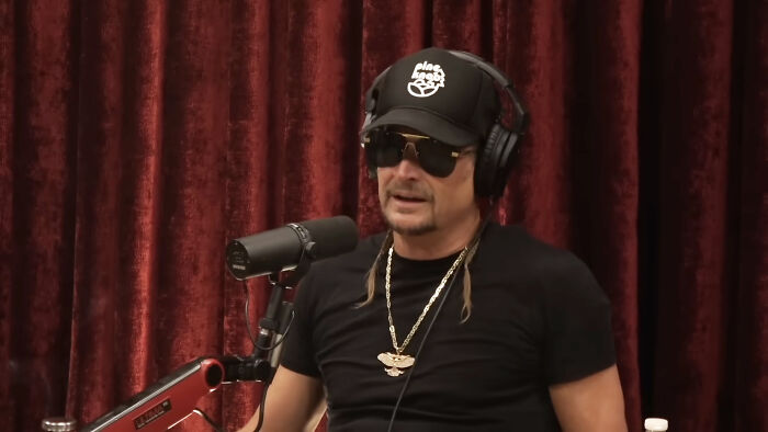 Celebrity wearing headphones and sunglasses, speaking into a microphone. Has this celebritys fame run out?