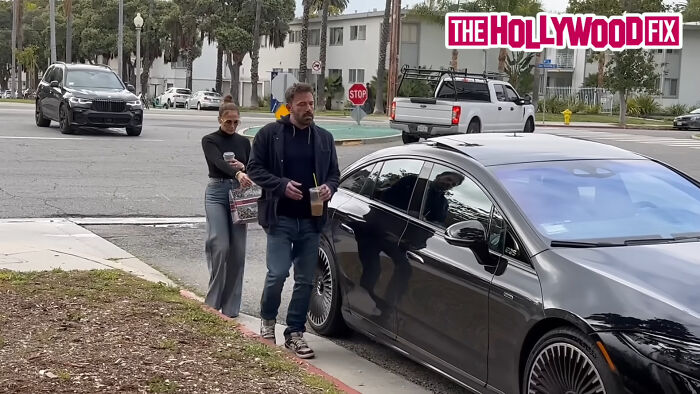 Ben Affleck and Jennifer Lopez walking near a car on the street, part of ongoing celebrity scandals.