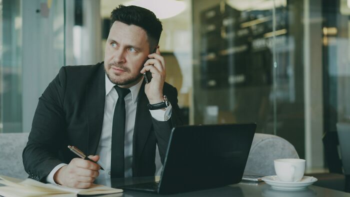 Man in suit talking on phone and working as a step to feel better post betrayal