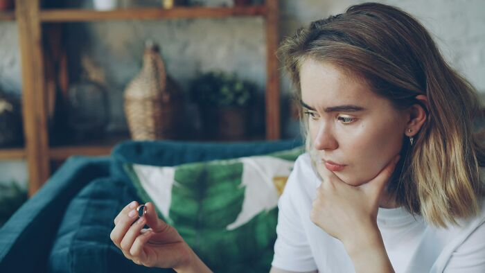 Thoughtful woman holding ring pondering exes unhinged relationship posts