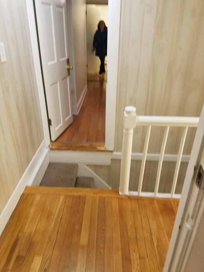 A woman stands at the end of a hallway, above a dangerous and unexpected drop where steps are missing, an architecture and design fail.