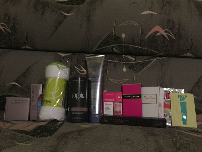 Various hair and beauty products, including Toppik, Murad, and Jose Maran, on a patterned couch.