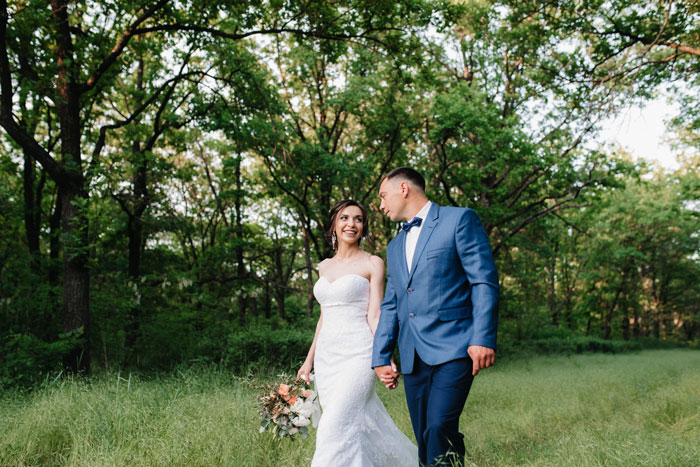Bride and groom walking hand in hand in a forest wedding setting Bride and groom walking hand in hand in a forest wedding setting